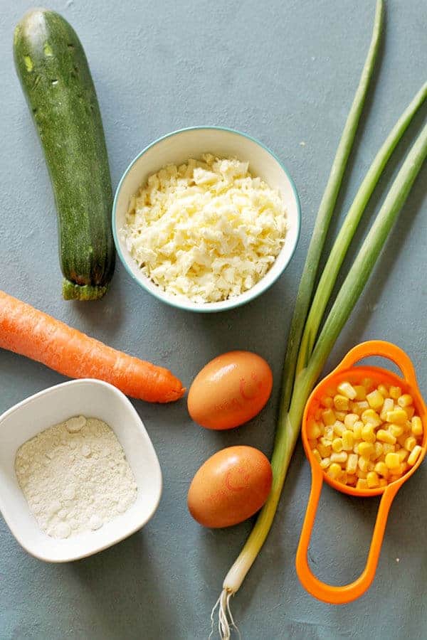 zucchini haloumi fritters ingredients laid on top of a blue background