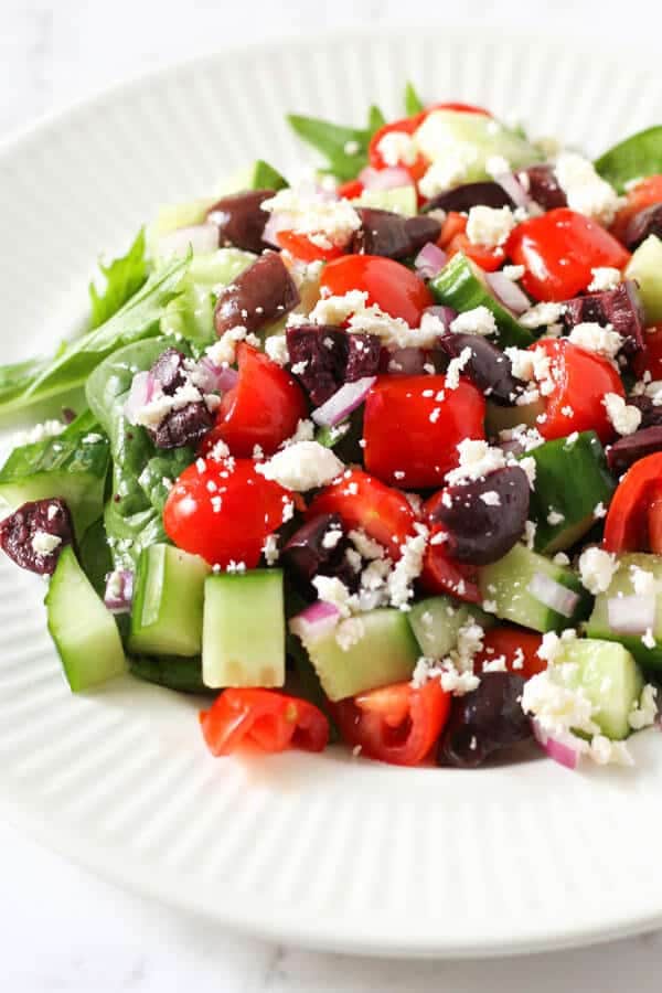 close up image of a greek salad on a white plate
