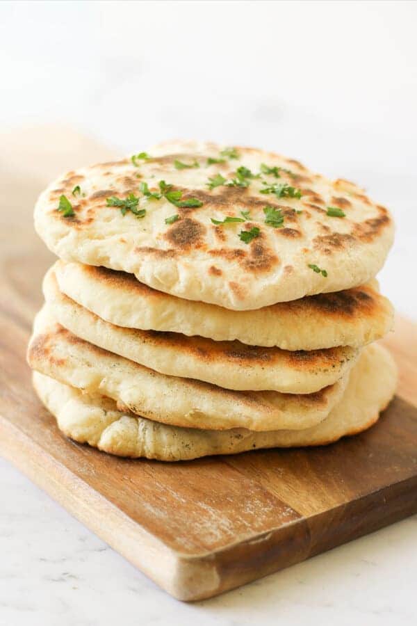 yoghurt flatbreads stacked on top of each other on a wooden board.
