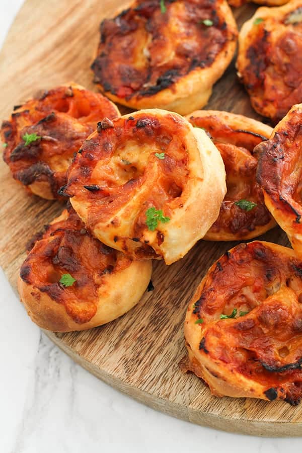 pizza scrolls stacked together on a wooden board.