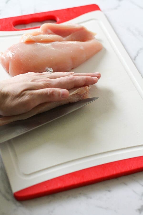 Chicken breast being cut in half.