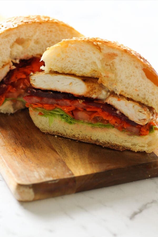 Grilled Chicken Burger cut in half on a wooden board.