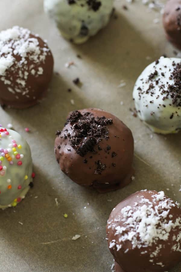oreo balls laying on baking tray covered in cookie crumbs and sprinkles.