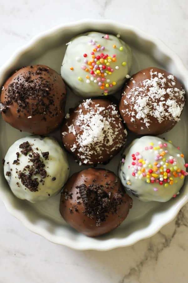 oreo balls laying on baking tray covered in cookie crumbs and sprinkles.