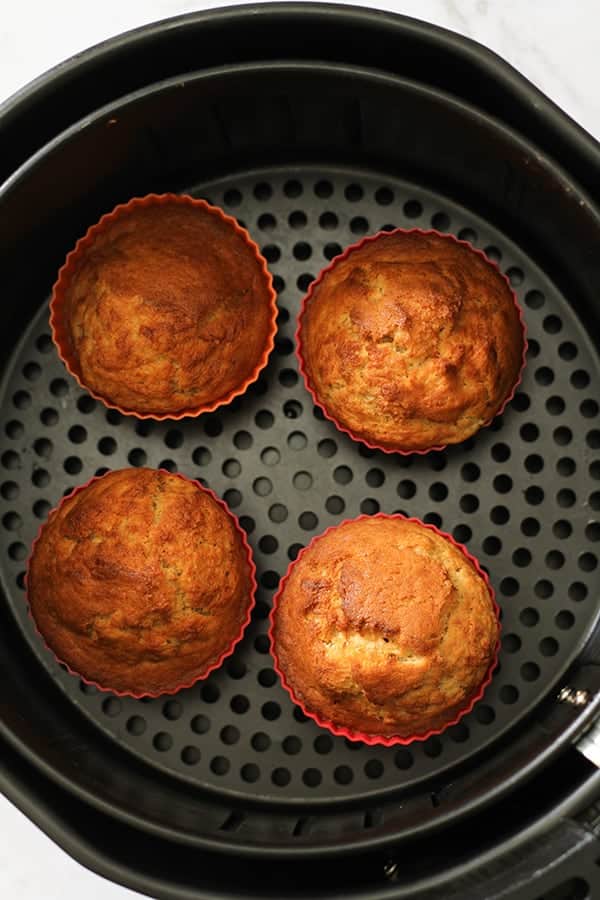 banana muffins in silicone muffin cases inside an air fryer basket.