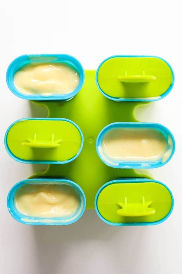 popsicle molds filled with mango pineapple popsicle mixture.