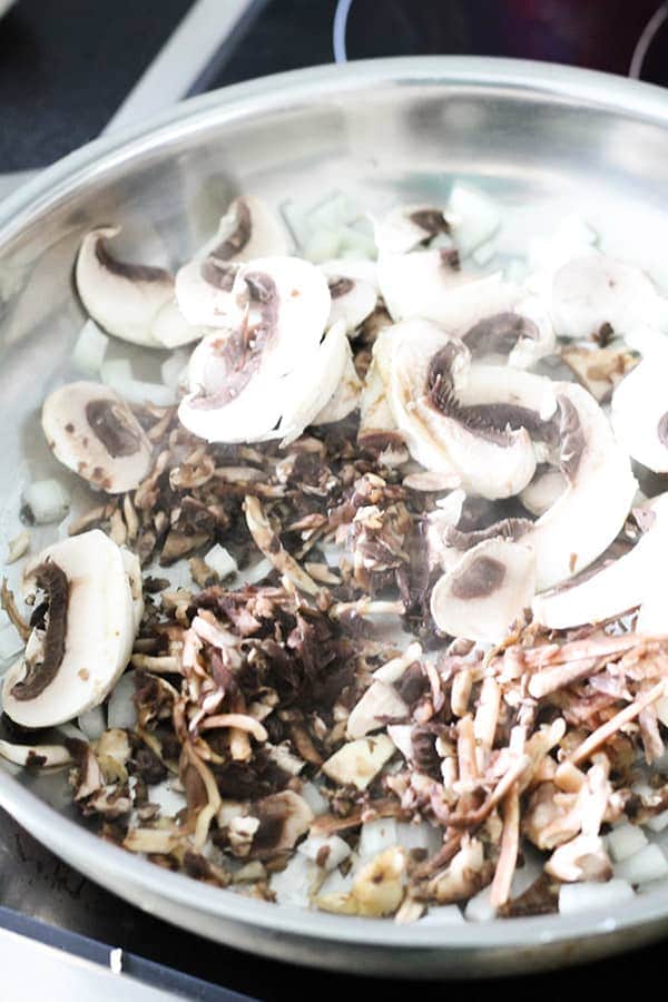mushrooms and onion sautéing in a frying pan.