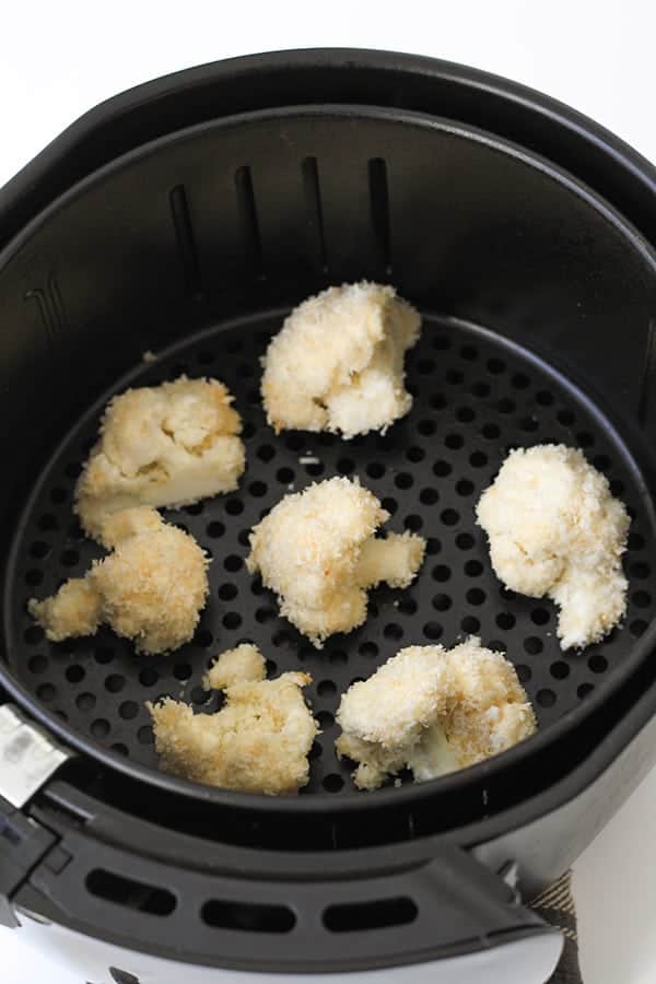 cauliflower pieces in an air fryer basket.