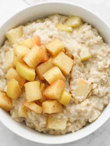 apple cinnamon oatmeal in a white bowl topped with stewed apples.