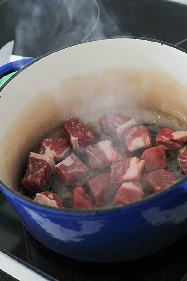 cubes of beef cooking in a dutch oven.