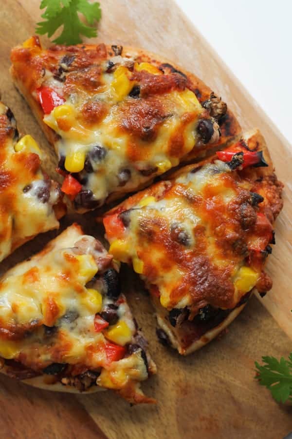 pizza cut into quarters on a wooden board.