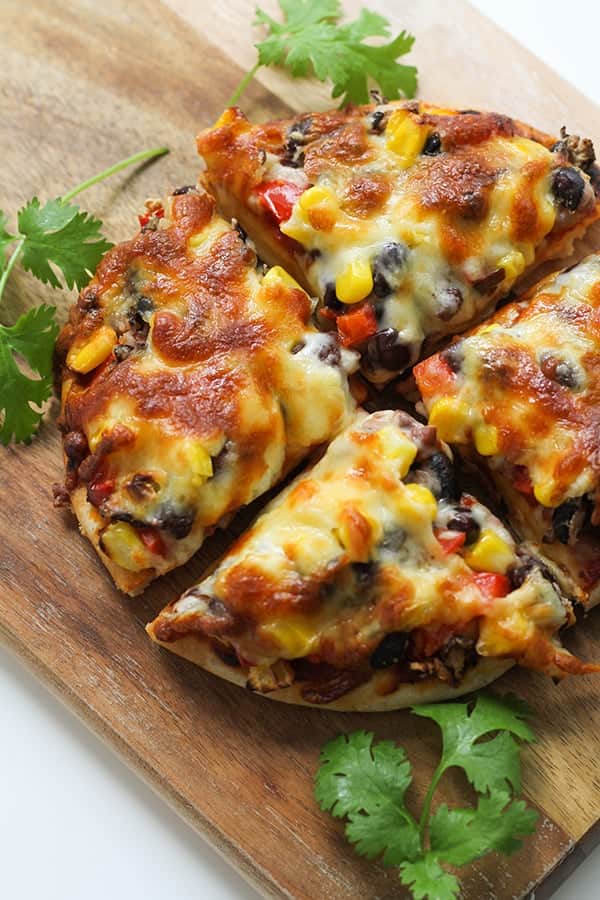 pizza cut into quarters on a wooden board.
