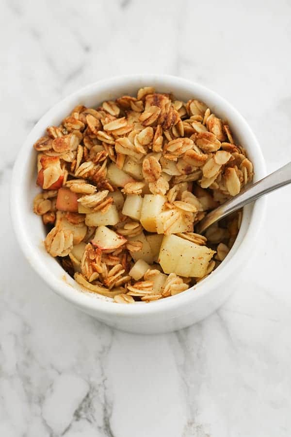 apple crisp in a white ramekin with a spoon.