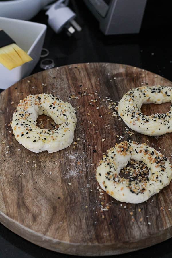 uncooked bagels on a wooden board.