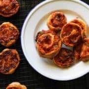 pizza pinwheels piled up on a white plate.