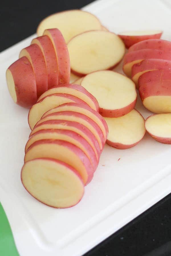 potato sliced into rounds on a chopping board.