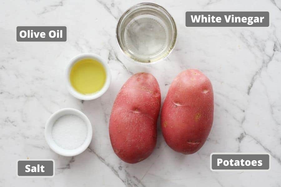 ingredients for salt and vinegar potatoes on a white marble background.
