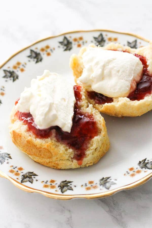 scone topped with jam and cream on a plate.