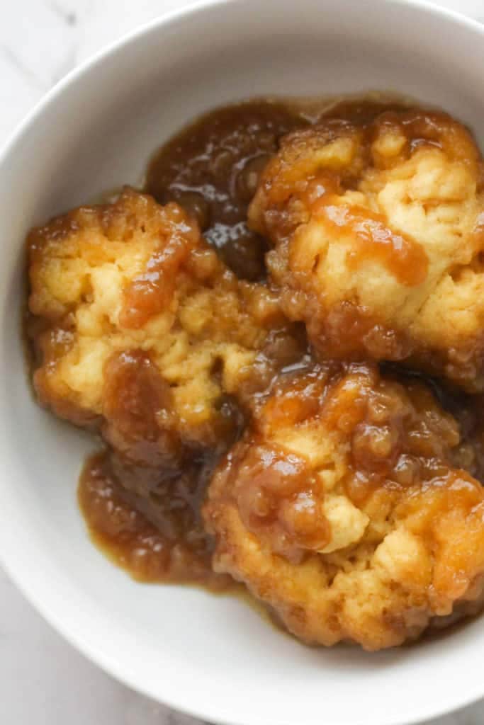 thick caramel dumplings covered in caramel sauce in a white bowl.