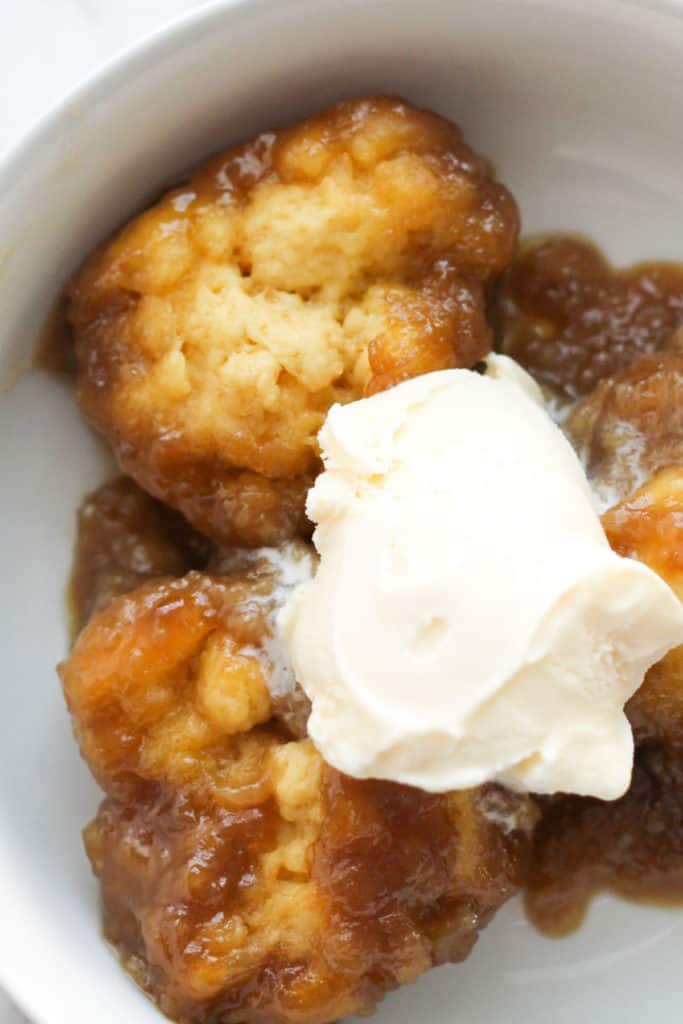 caramel dumplings with ice cream on top in a white bowl.