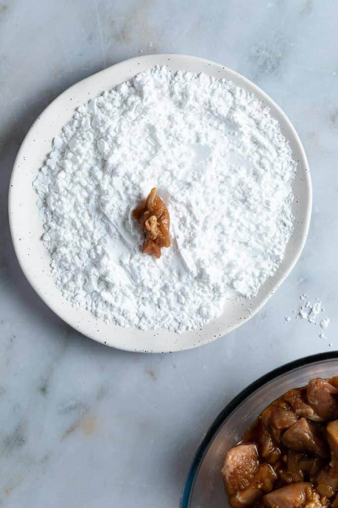a raw chicken pieces on a plate of potato flour.